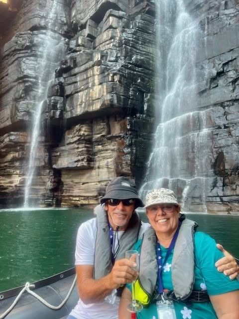 Lisa on a boat beneath a waterfall in the Kimberley